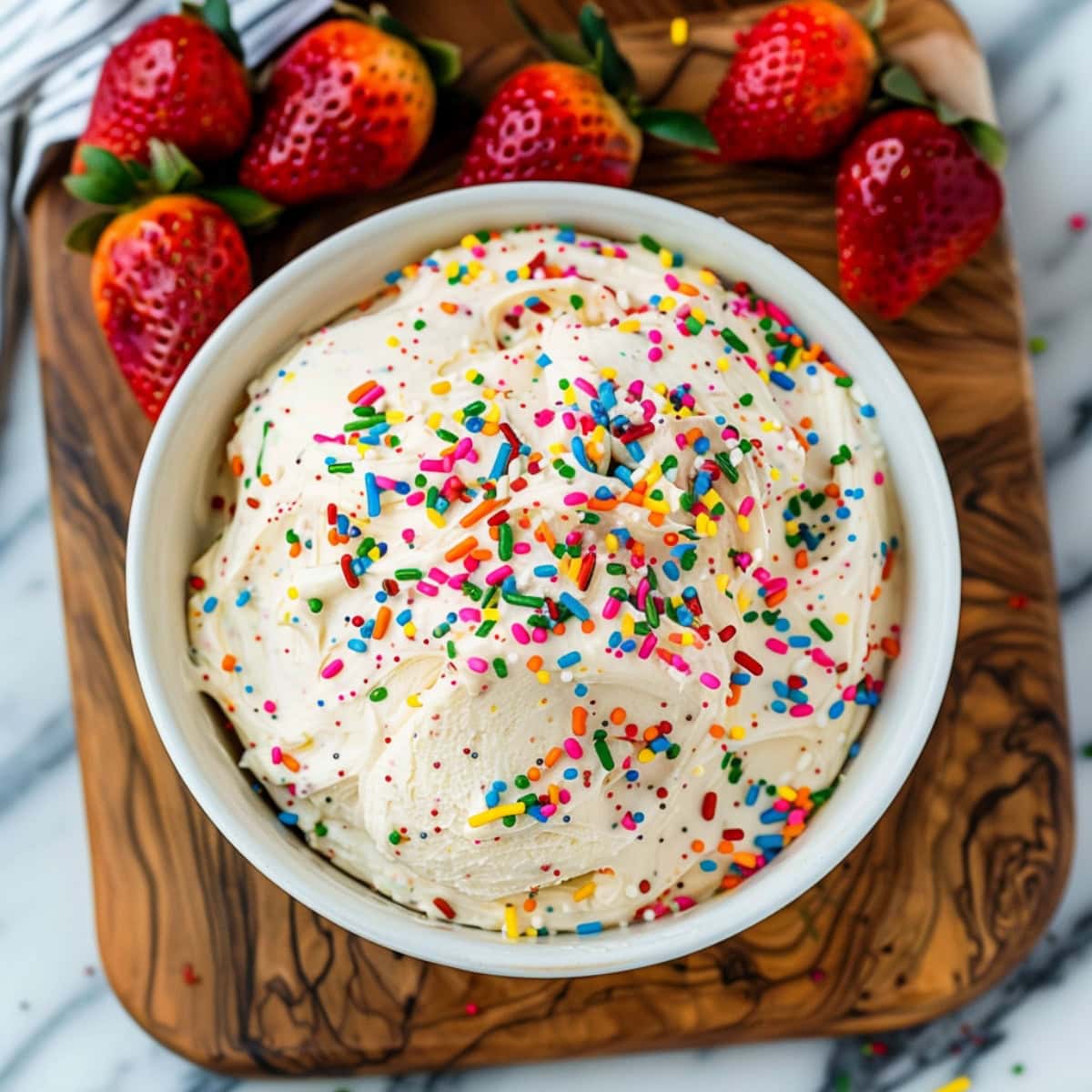 Delicious funfetti cake dip, garnished with extra sprinkles and served with fresh strawberries.