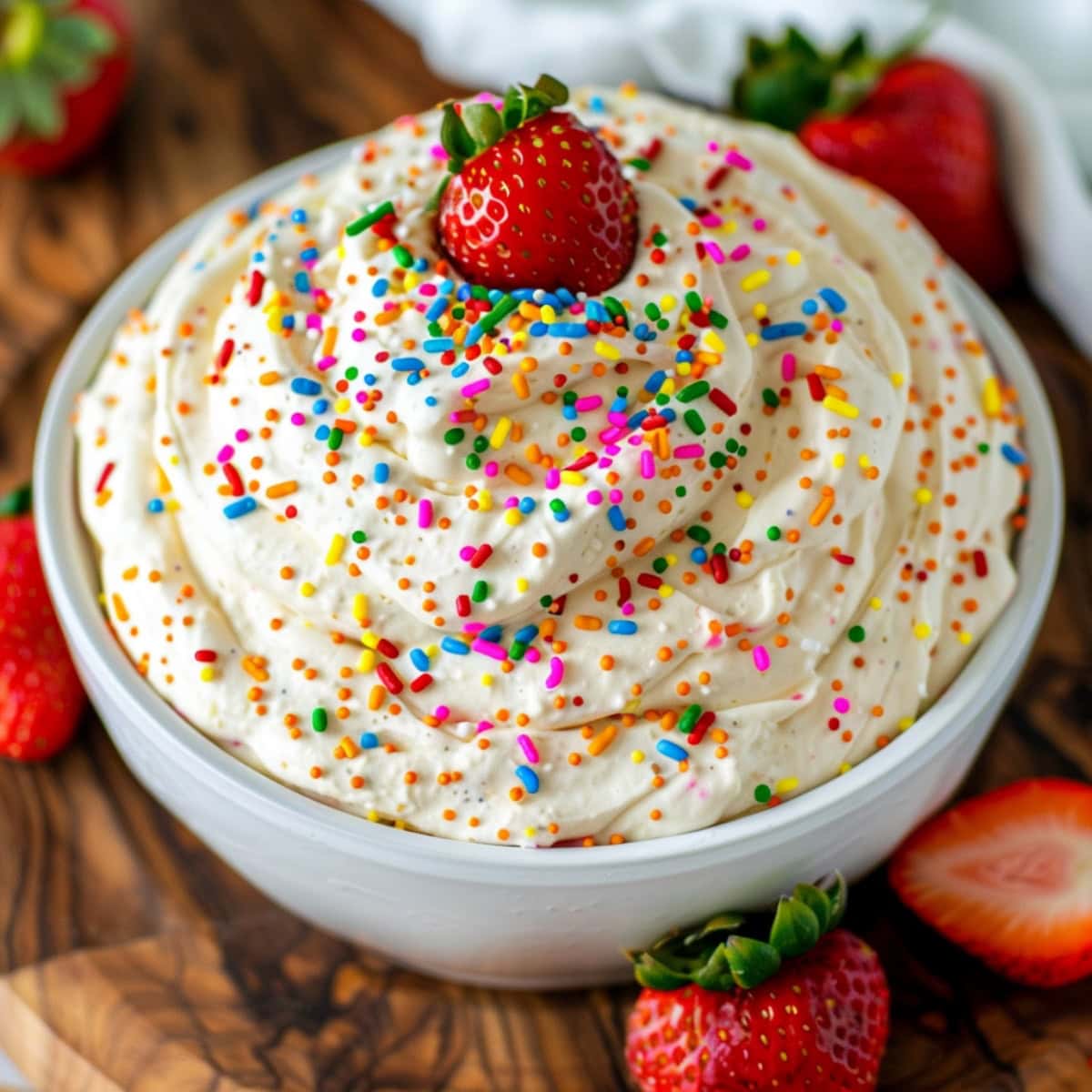 Colorful funfetti cake dip, topped with rainbow sprinkles and a strawberry.