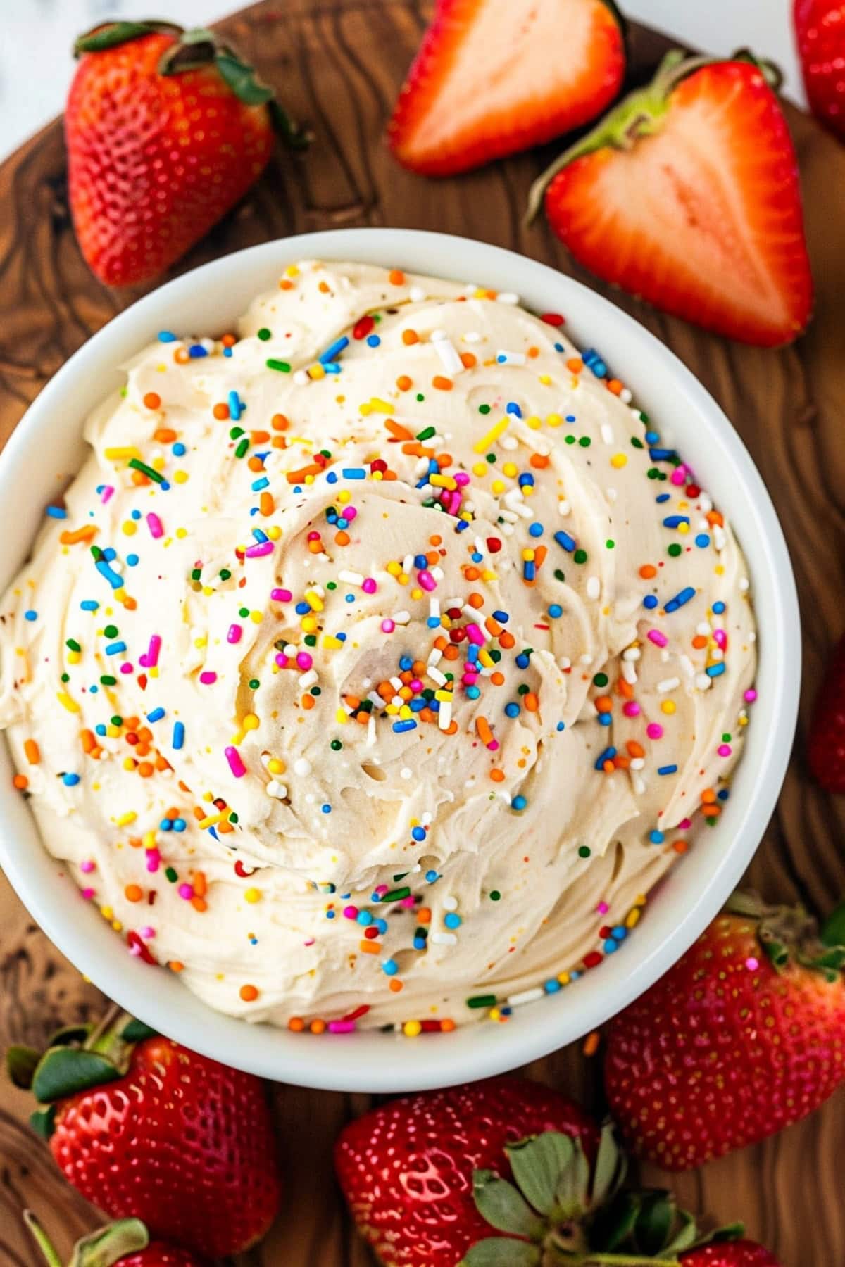 Creamy homemade funfetti cake dip in a bowl with strawberries on the side.