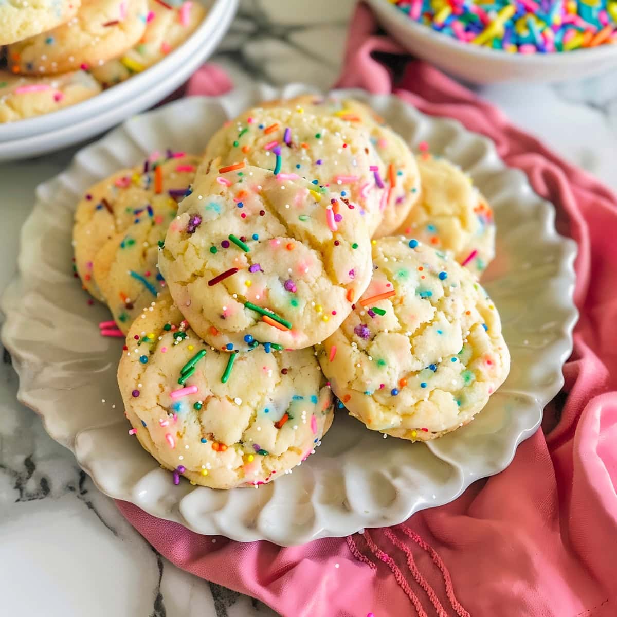 Funfetti cake mix cookies on a white plate with colorful sprinkles.