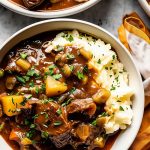 Three Bowls of Delicious Guinness Beef Stew Over Mashed Potatoes with a Yellow Kitchen Towels