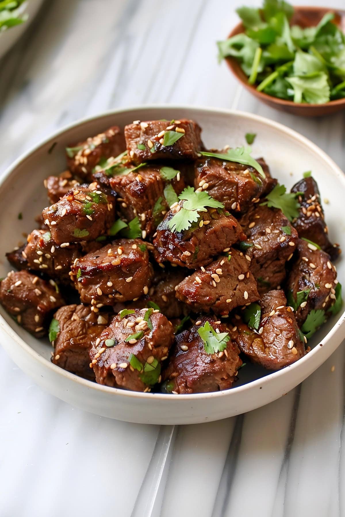 Asian steak bites garnished with cilantro and sesame seeds