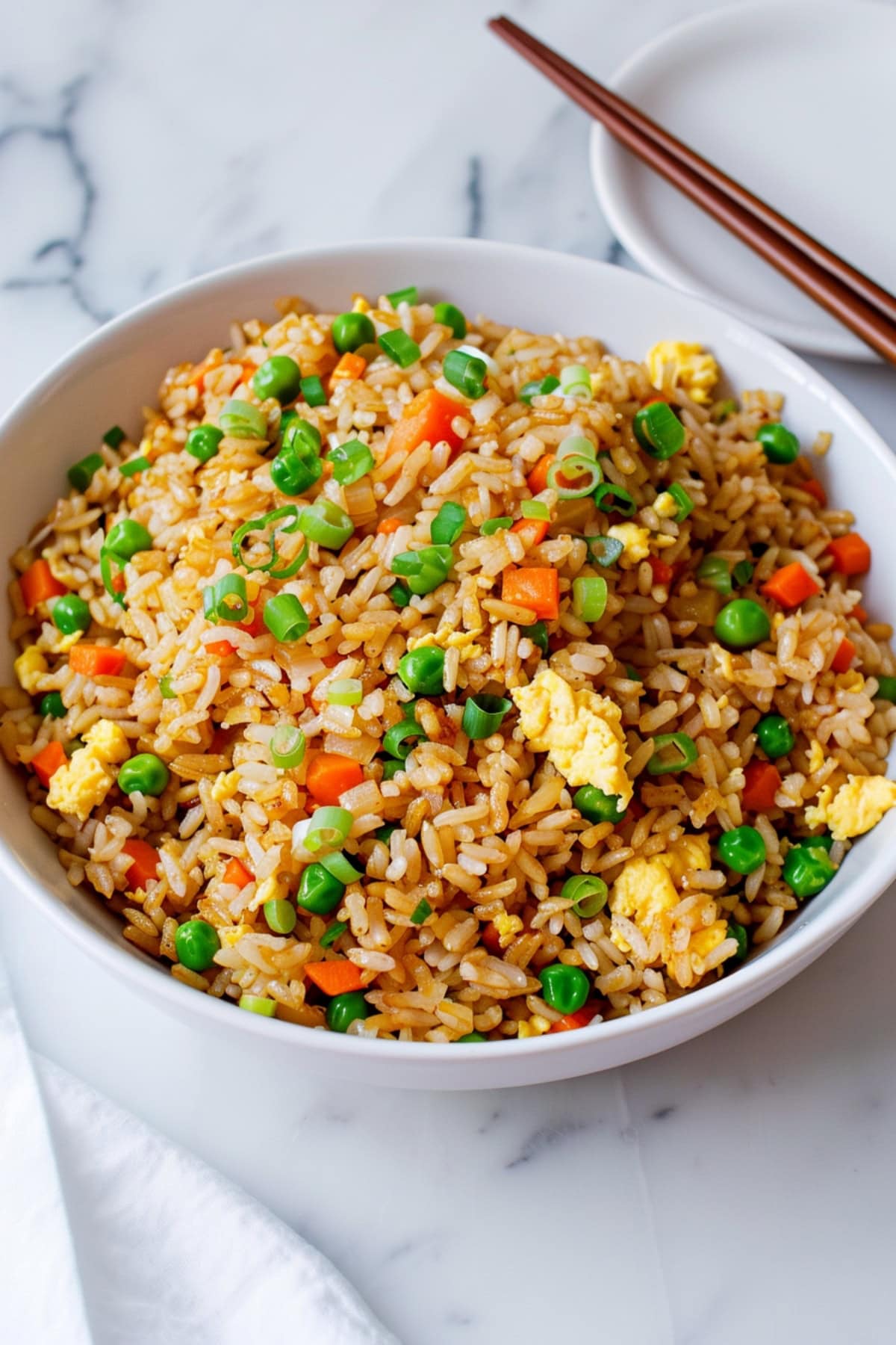 Homemade hibachi fried rice, prepared with fresh ingredients including green onions, green peas and carrots, and a touch of soy sauce for authentic flavor