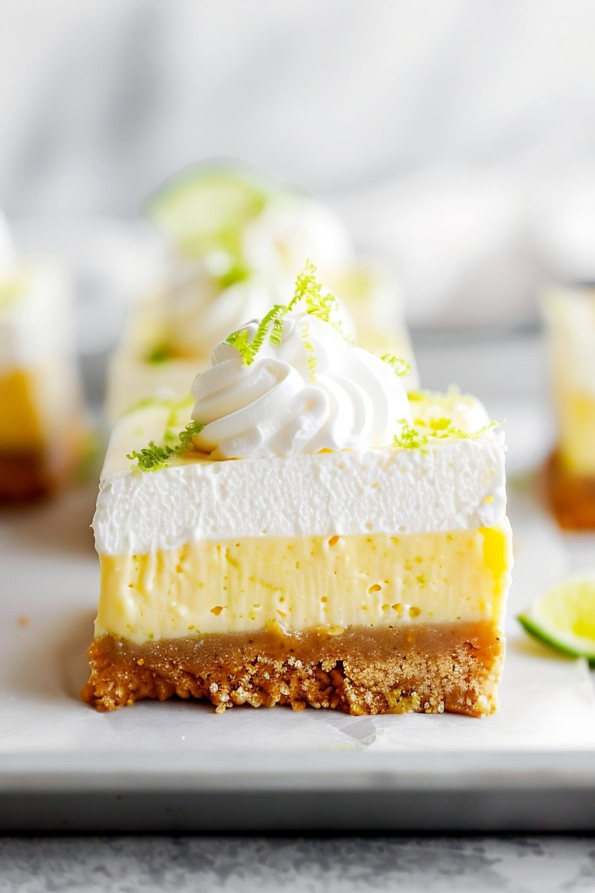 Flavorful homemade key lime squares, featuring a smooth and velvety filling and a thick layer of whipped cream on top