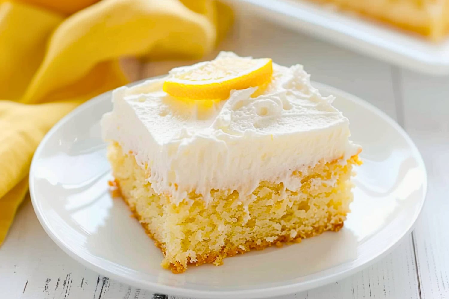 Slice of moist lemon crazy cake on a white plate garnished with lemon slice.
