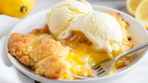 Lemon cobbler in plate with two scoops of vanilla ice cream.