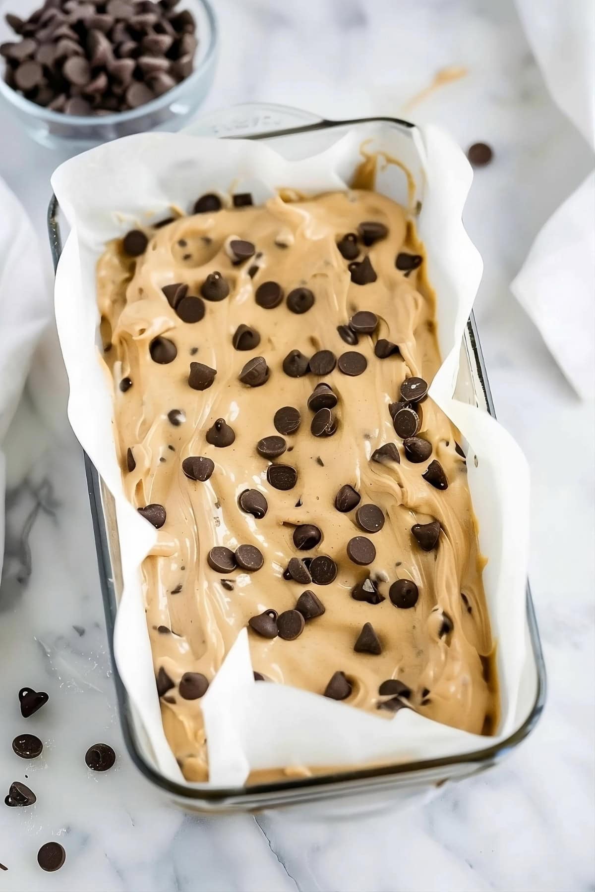 Banana and peanut butter bread batter mix in a loaf pan with chocolate chips on top, top down view.