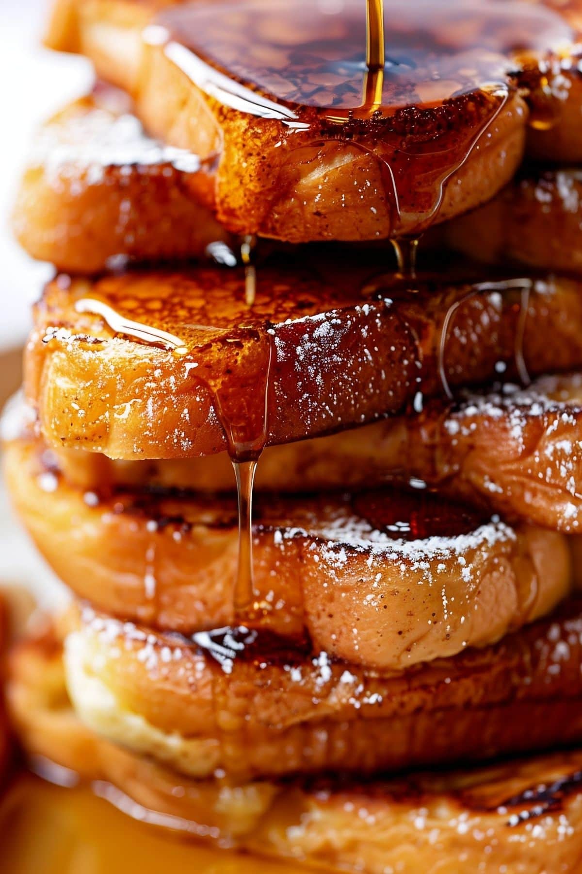 Super Close Up of a Stack of McCormick French Toast with Powdered Sugar and Maple Syrup Dripping Down the Side