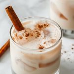 Creamy Mexican Horchata with Ice in a Glass with Cinnamon Dusting and a Cinnamon Stick
