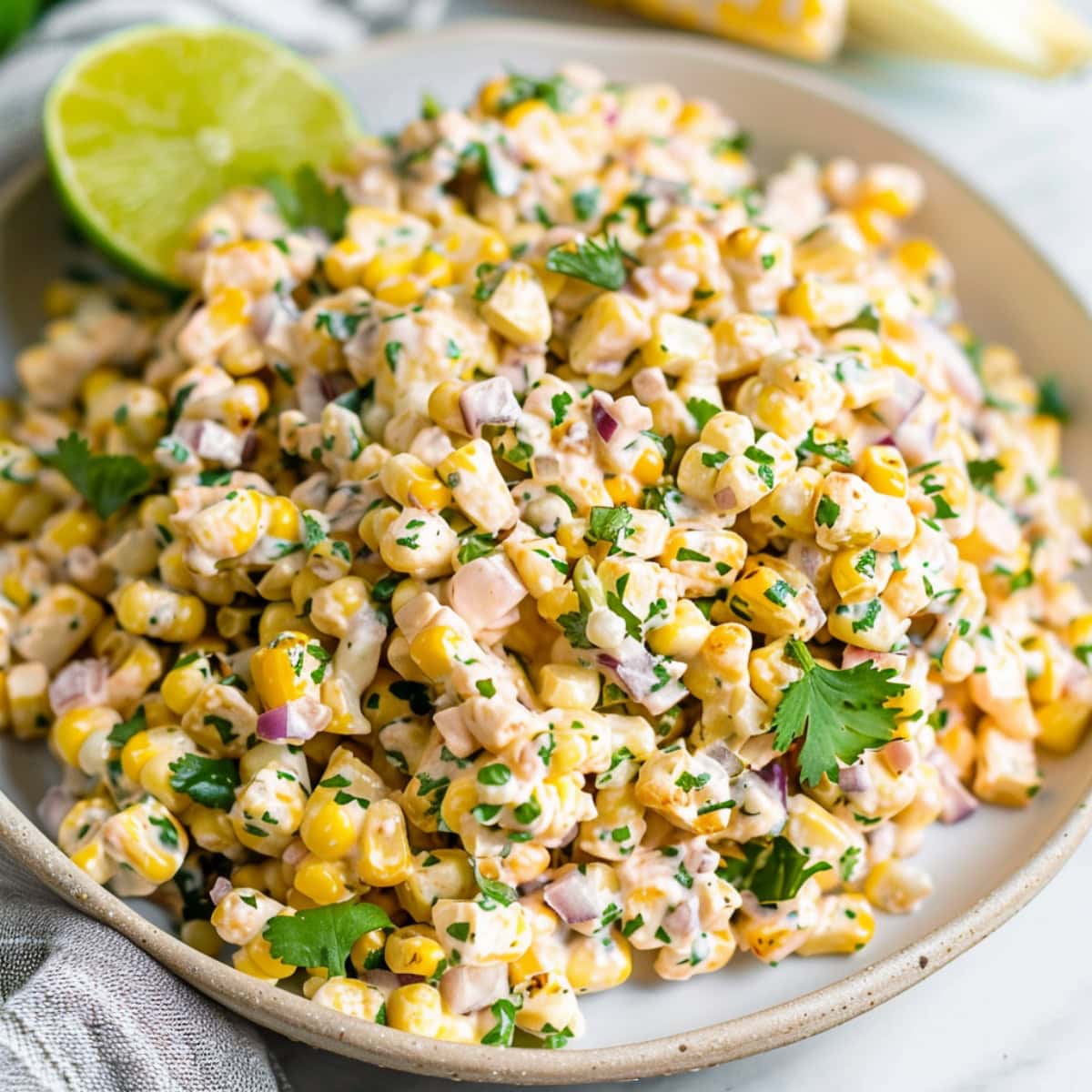 Creamy Mexican street corn salad with with lime and chopped red onions.