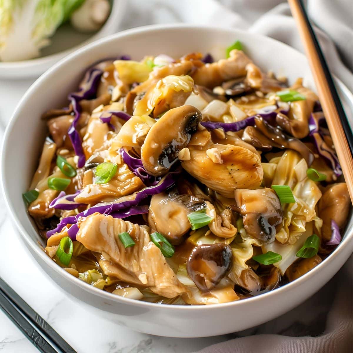 Moo Shu Chicken with Mushrooms, Onions, Cabbage, Garlic, Green Onions, in Sauce in a White Bowl with Chopsticks