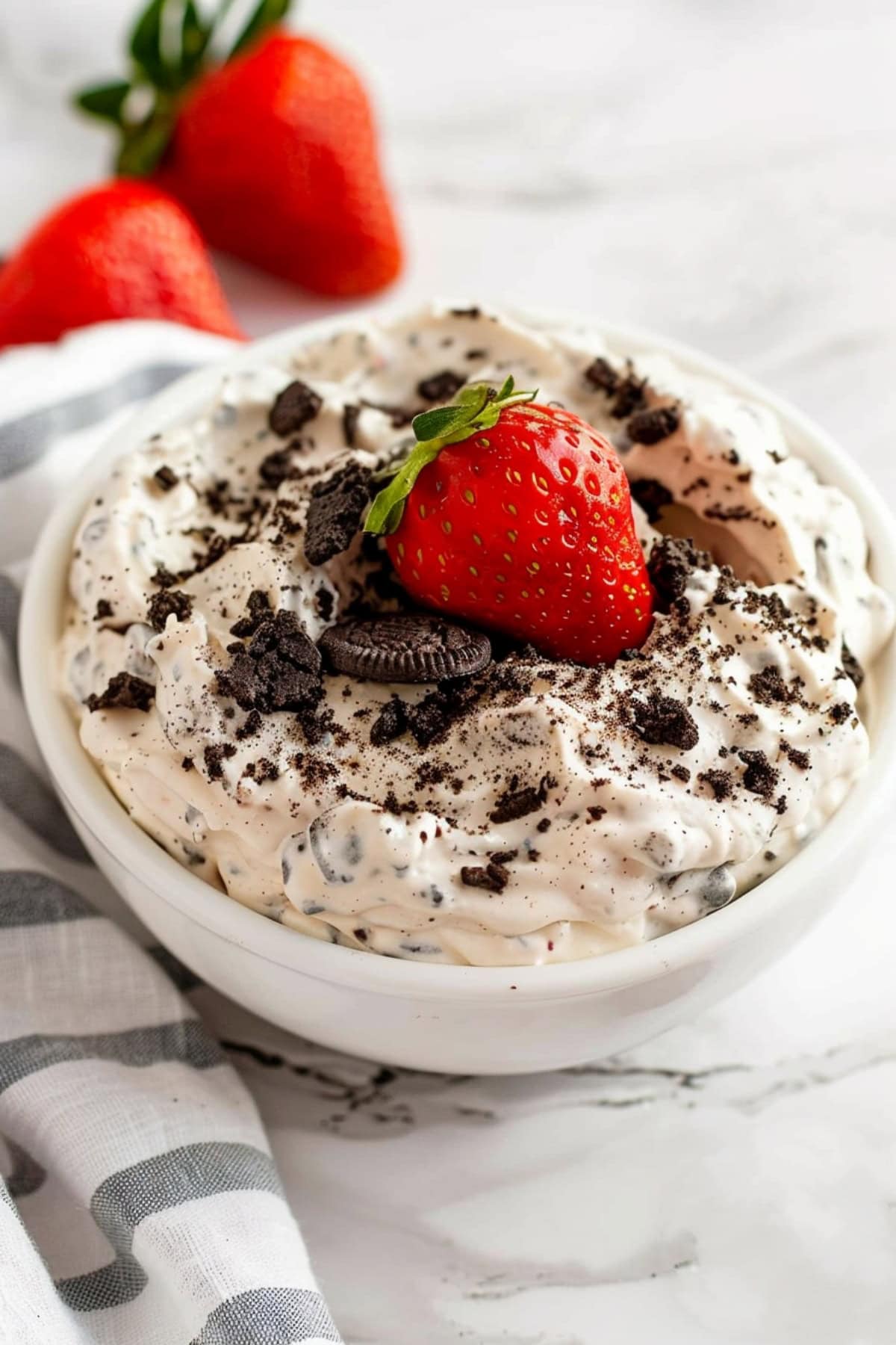 Bowl of homemade oreo dip topped with fresh strawberry