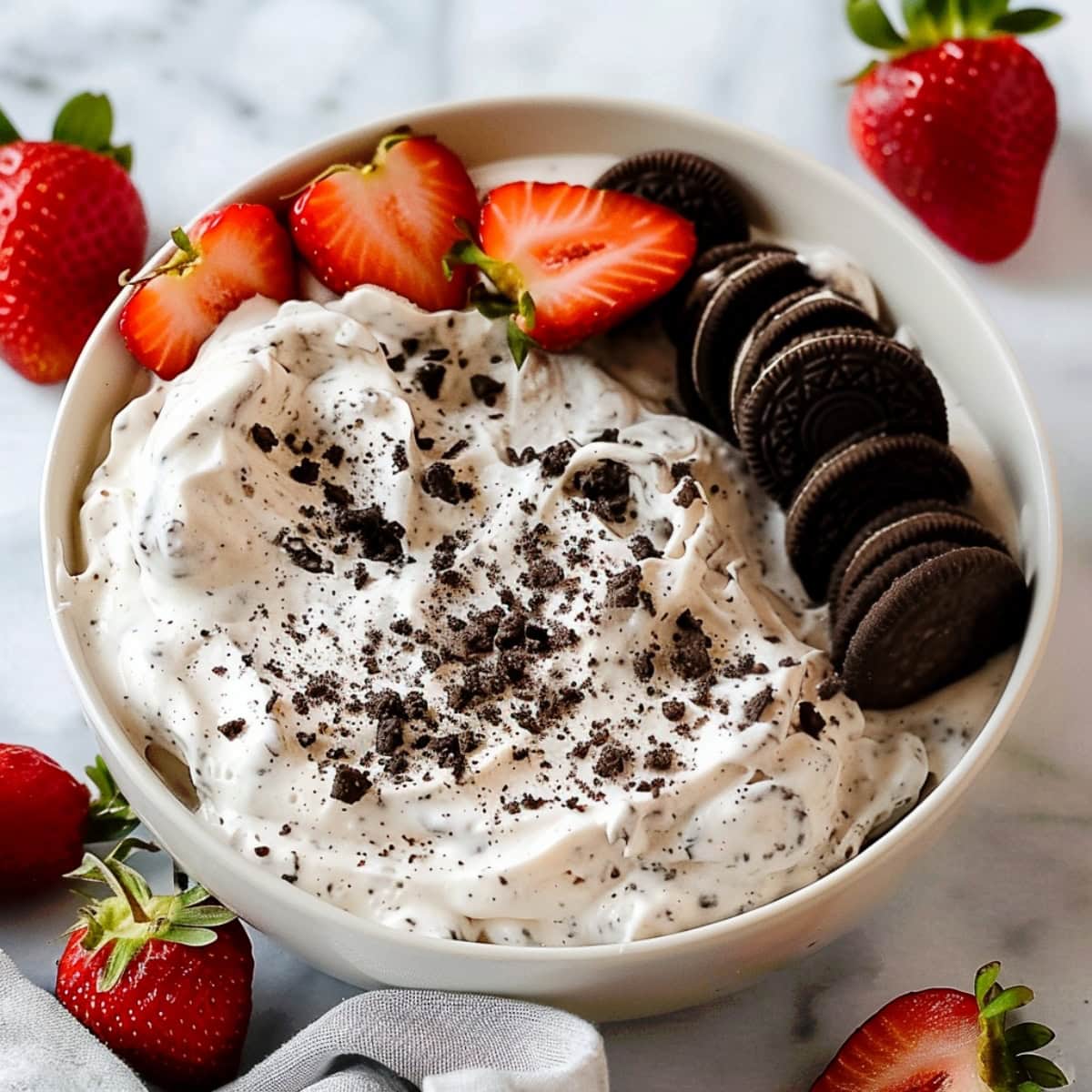A bowl of creamy Oreo dip surrounded by fresh strawberries and Oreo cookies