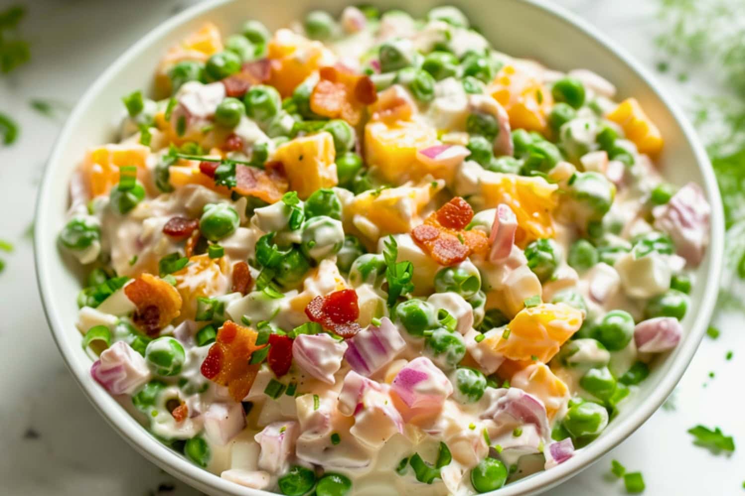Pea salad in a white bowl loaded with cheese, bacon, green peas, and red onion in creamy mayonnaise dressing.