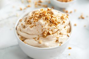Fluffy and creamy peanut butter dip in a white bowl topped with chopped peanuts.