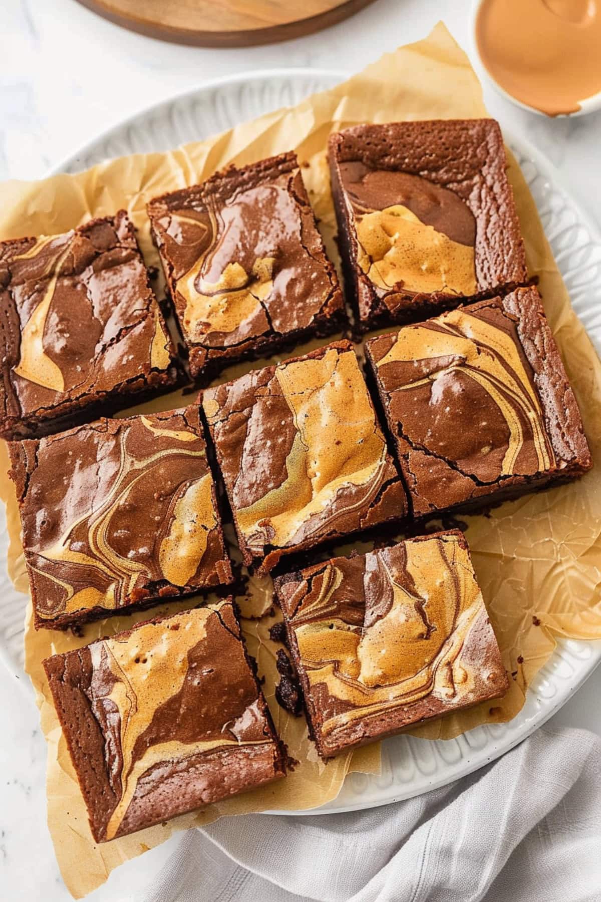 Sliced peanut butter brownies in a plate with parchment paper in white plate.