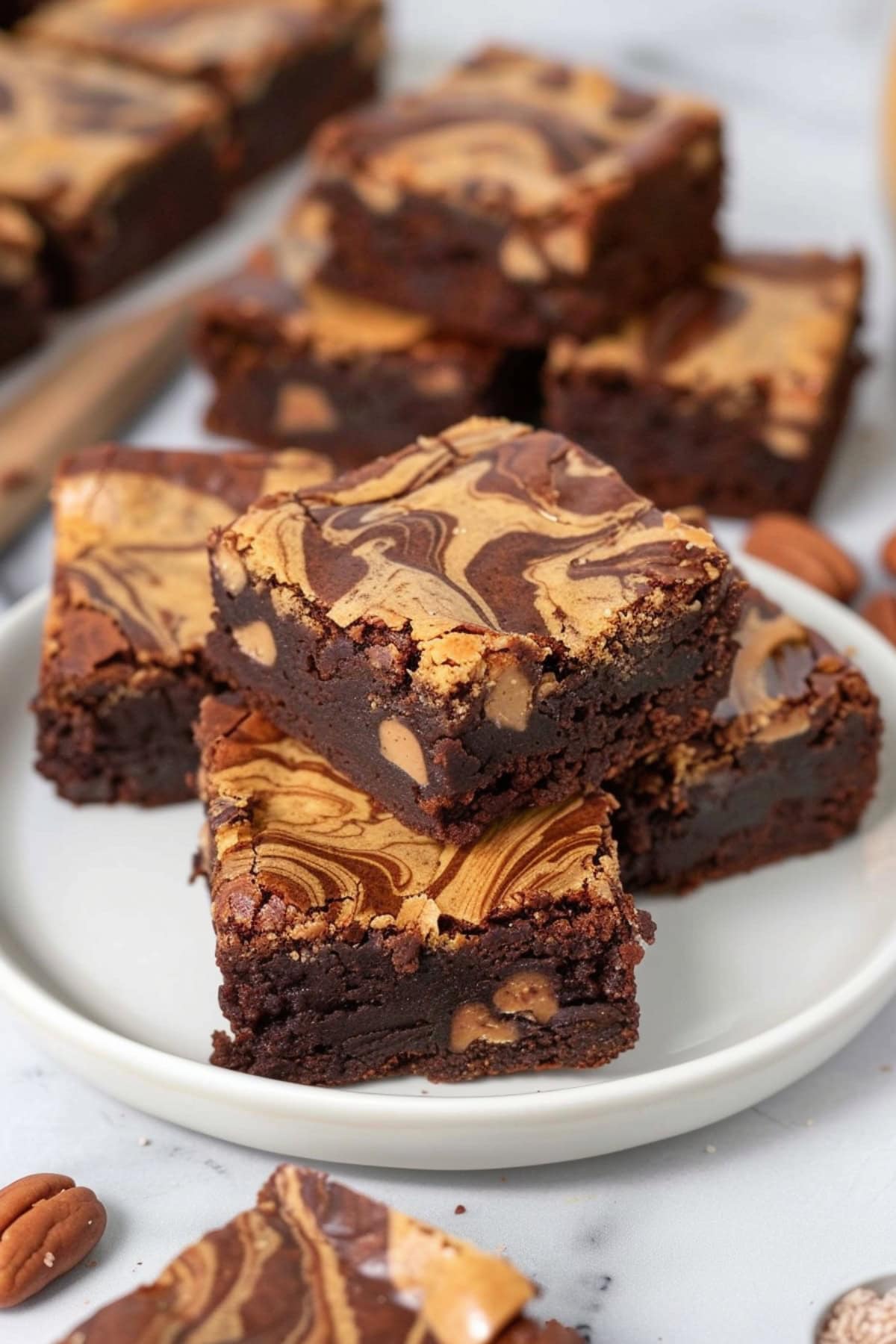 Squares of peanut butter swirl brownies stacked in a white plate.