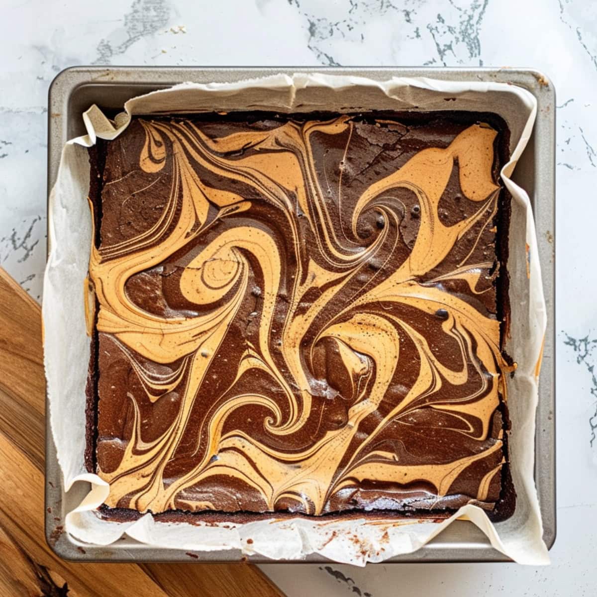 Whole peanut butter brownies in a baking pan with parchment paper.