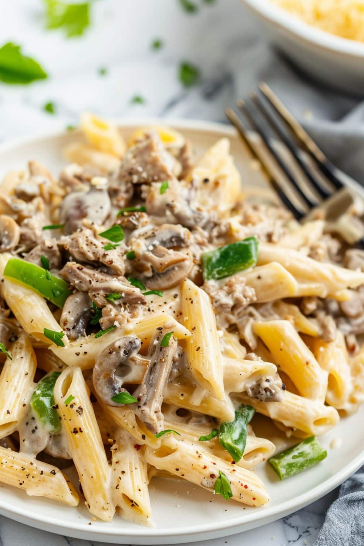 White plate with serving of Philly cheesesteak pasta.