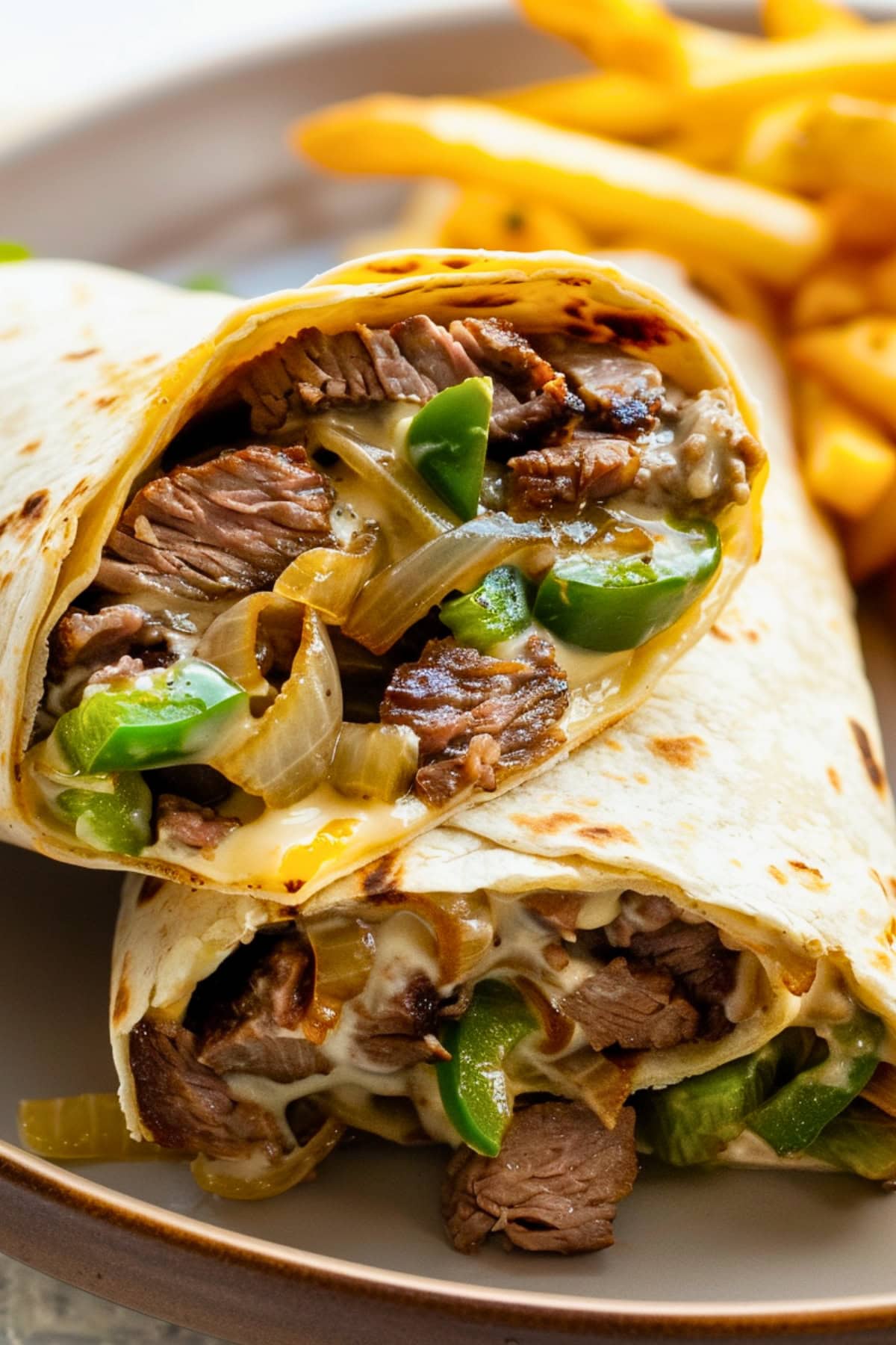 Tacos with a saucy cheesesteak filling and fries on a plate.