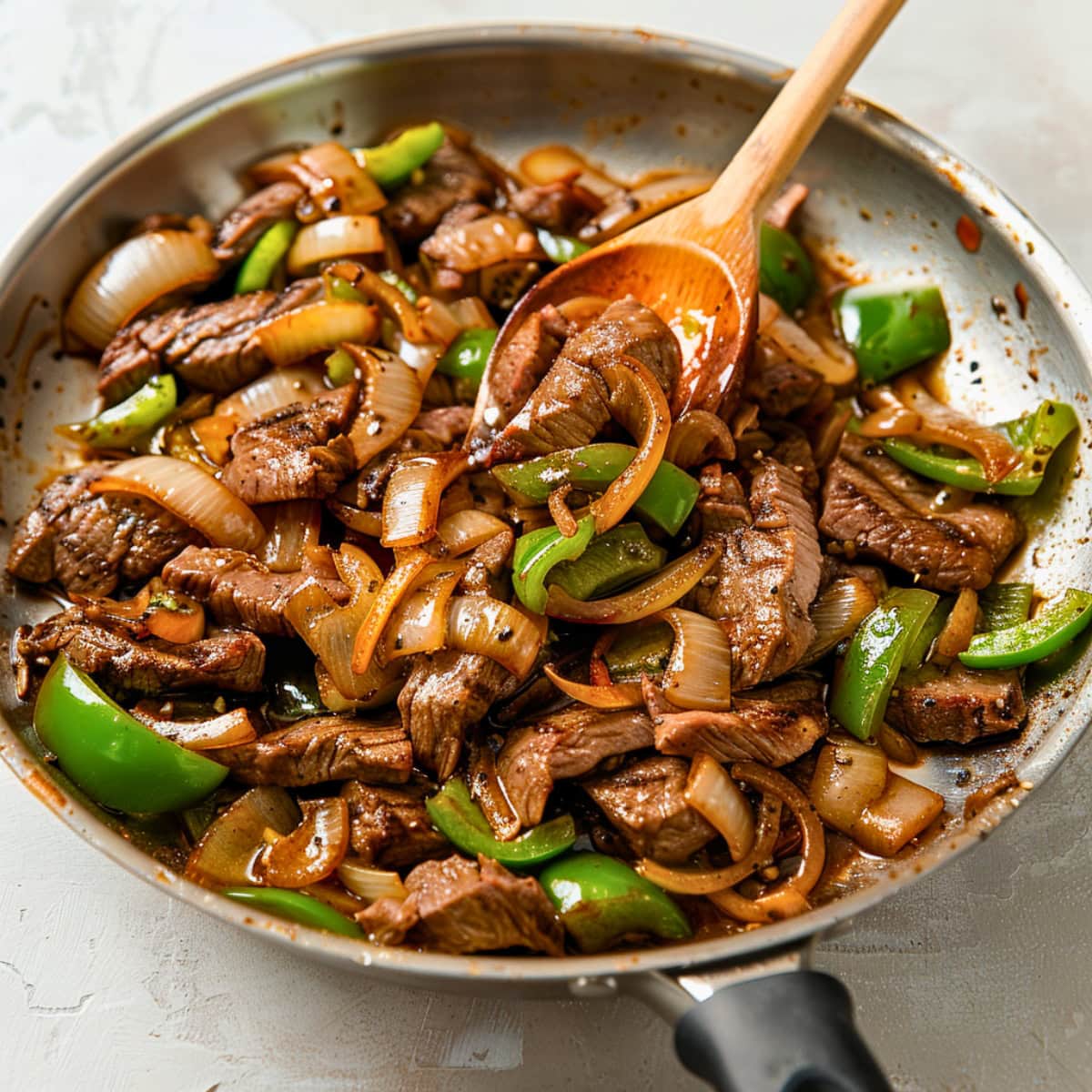 Sauteed onion, bell pepper and steak in a pan.