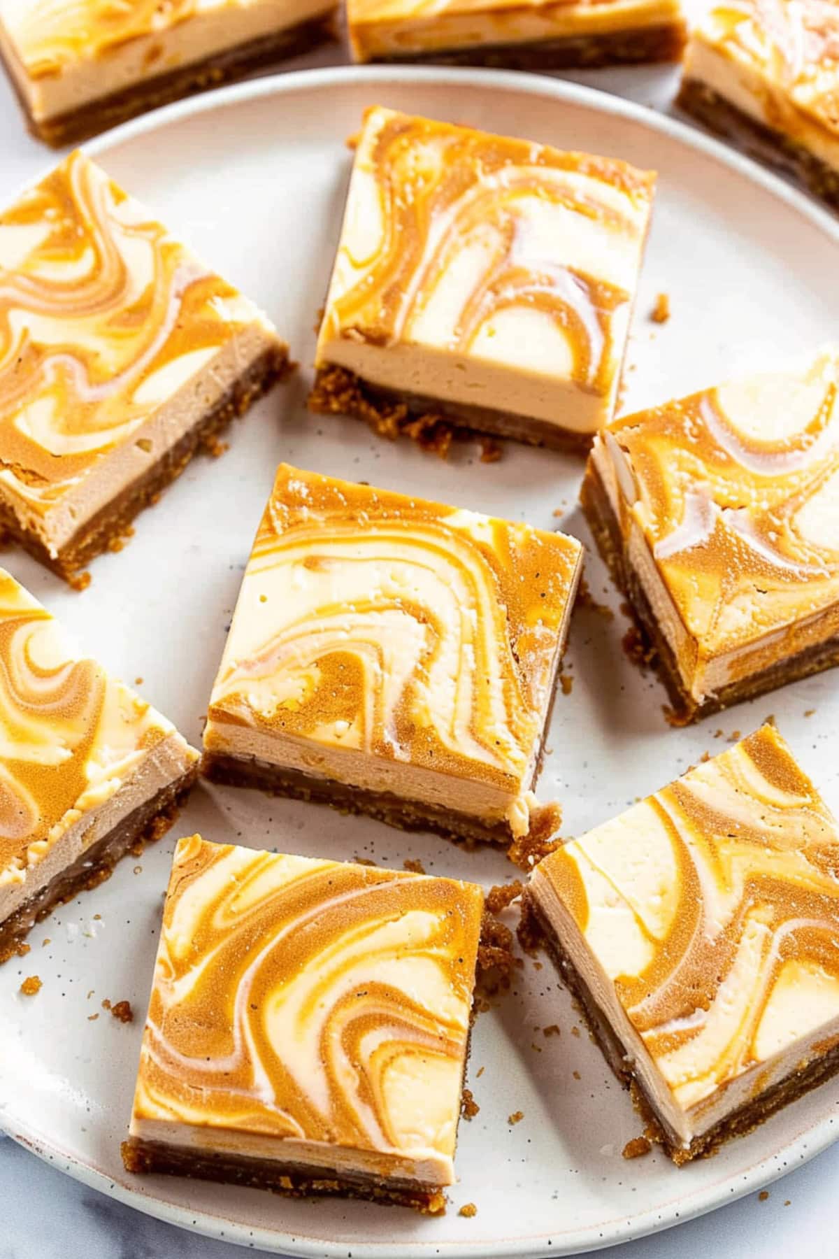 Squares of pumpkin cheesecake bars on white plate.