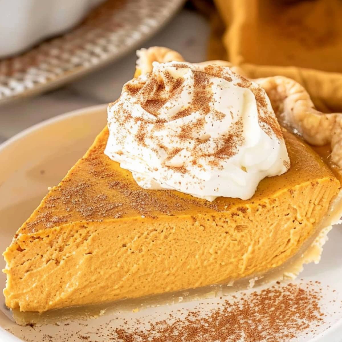Slice of pumpkin cream pie in a plate garnished with whipped cream, dusted with pumpkin spice.