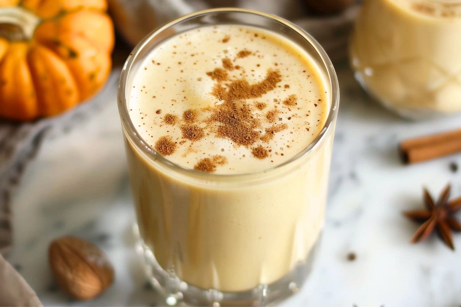 Spicy and creamy pumpkin eggnog in a glass with powdered nutmeg