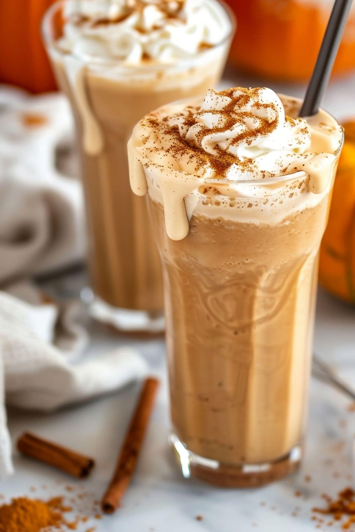 Close Up of Two Pumpkin Milkshakes with Whipped Cream and Cinnamon, and Creamy Milkshake Dripping Down the Sides