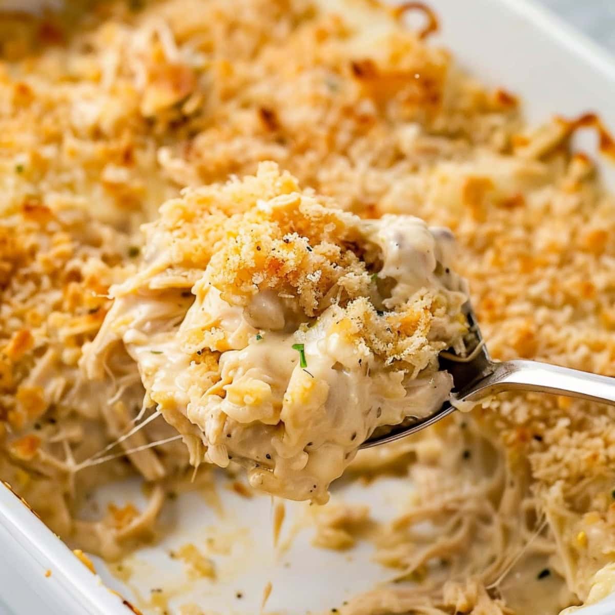 Spoonful of creamy chicken casserole with crushed Ritz crackers.