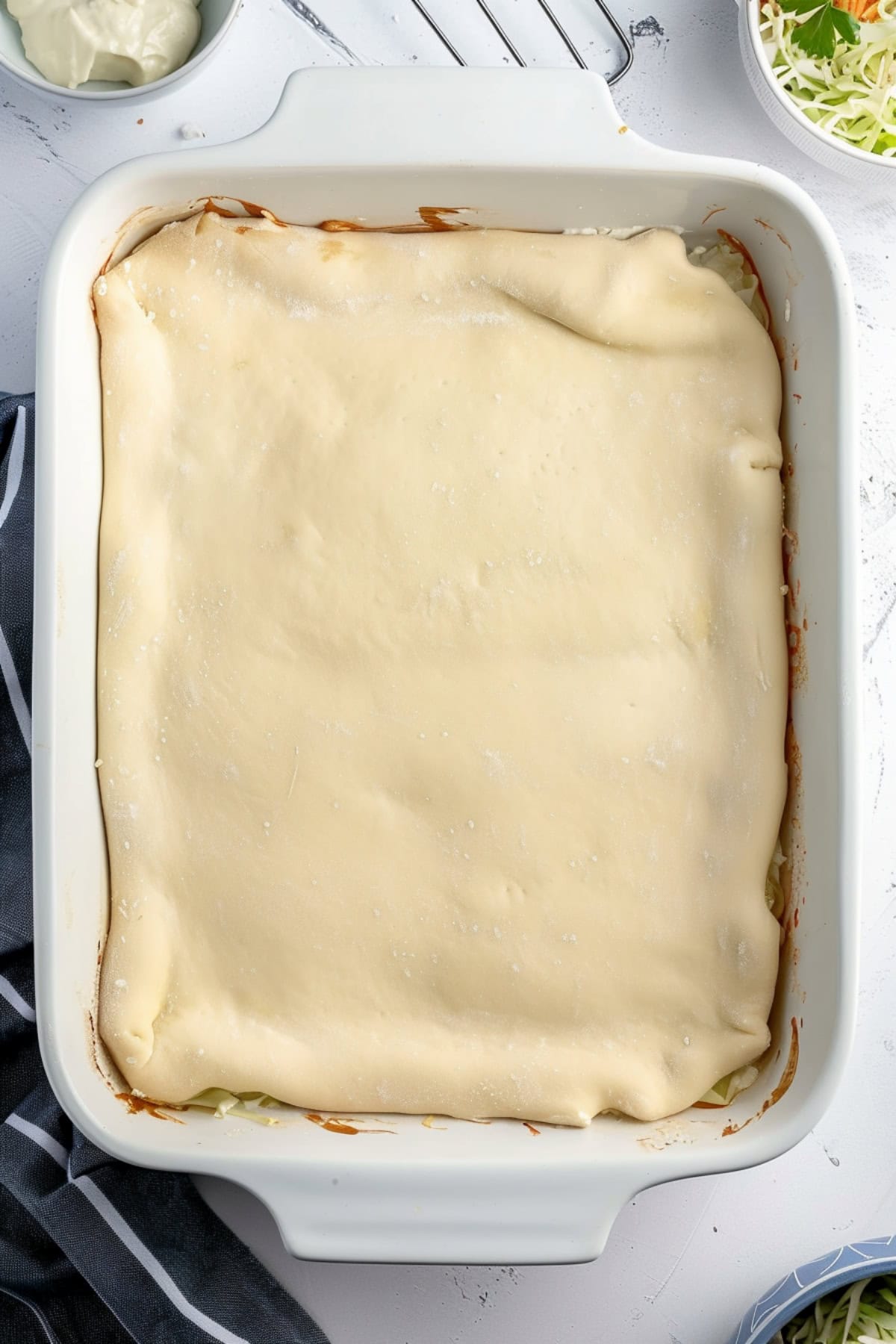 Runza casserole covered with crescent roll dough on a white baking dish.
