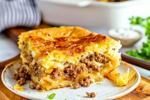 A slice of Runza casserole in a white plate with cabbage, cheese and ground pork filling.