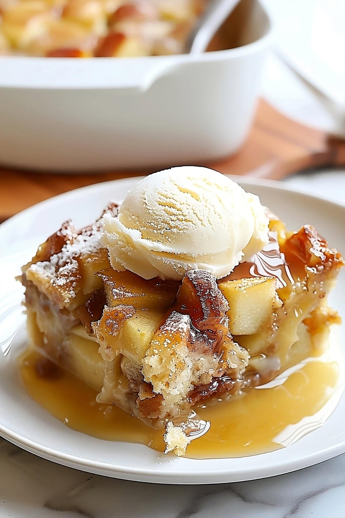 Apple pie bread pudding served in a white plate garnished with vanilla ice cream.