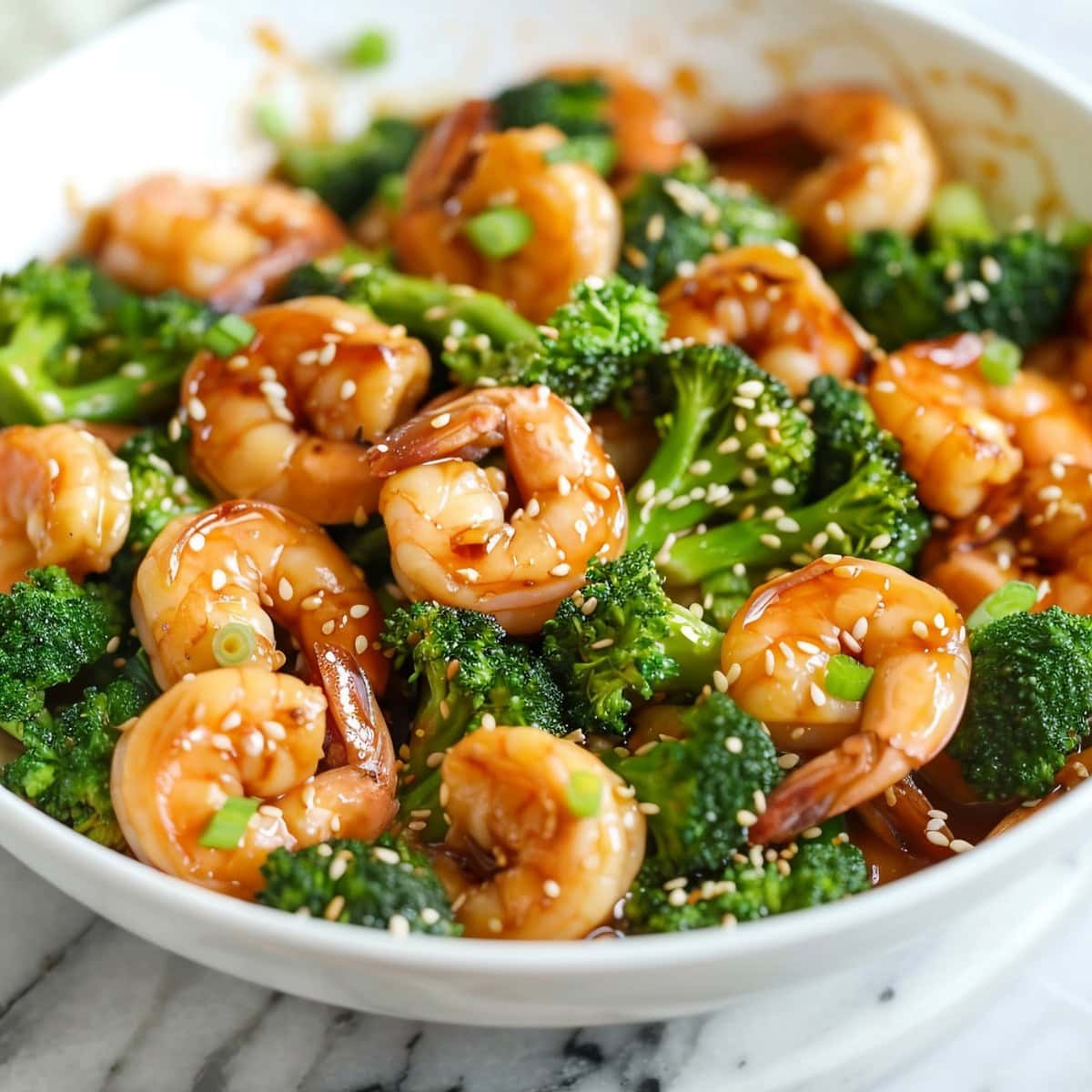 Homemade shrimp and broccoli stir-fry in a bowl with green onions and sesame seeds
