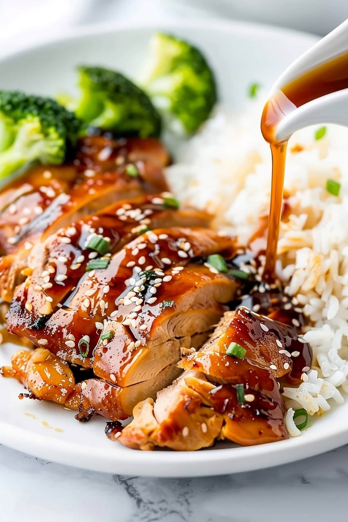 Teriyaki sauce poured to sliced chicken thigh with rice served with rice and broccoli