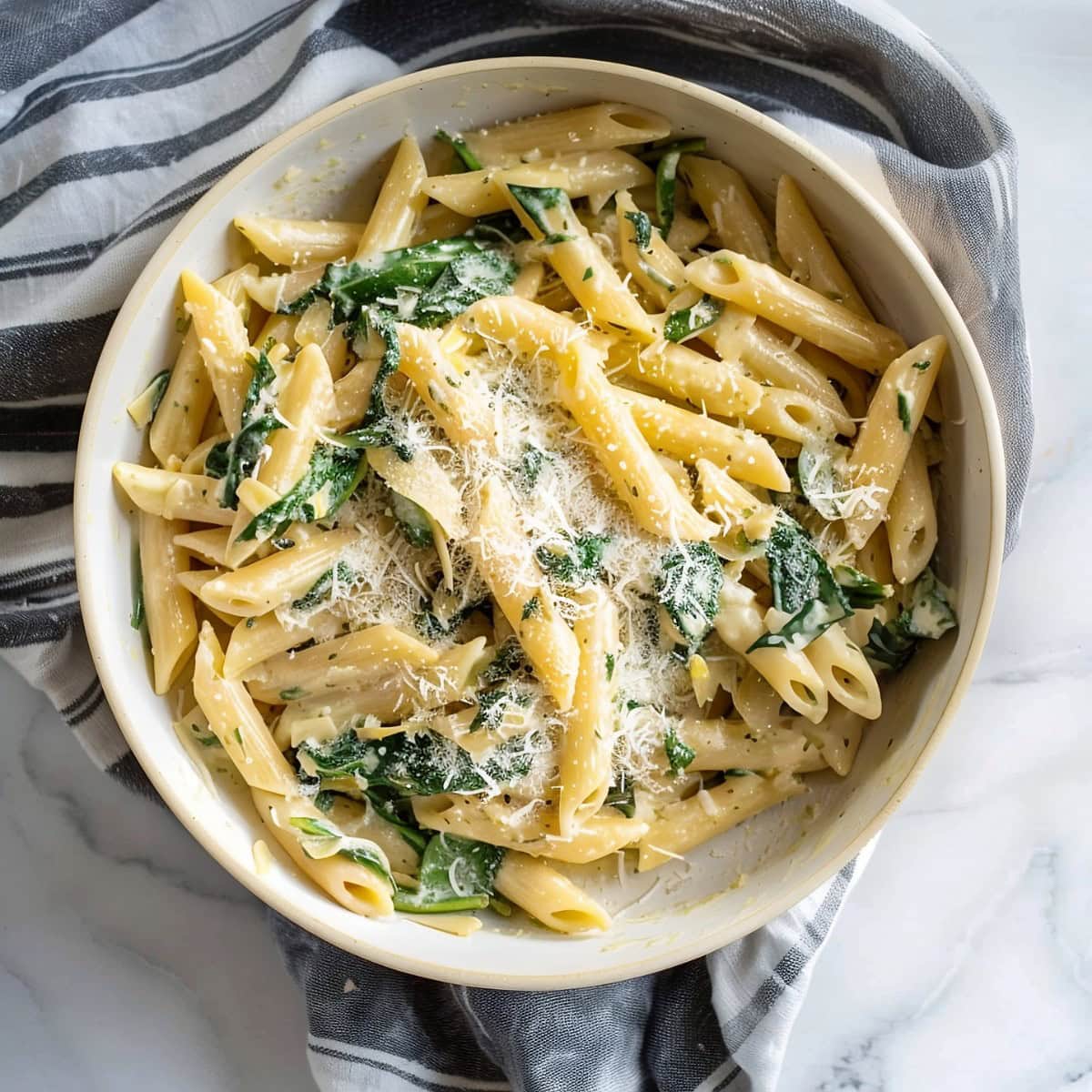Delicious and hearty spinach artichoke pasta in a white bowl