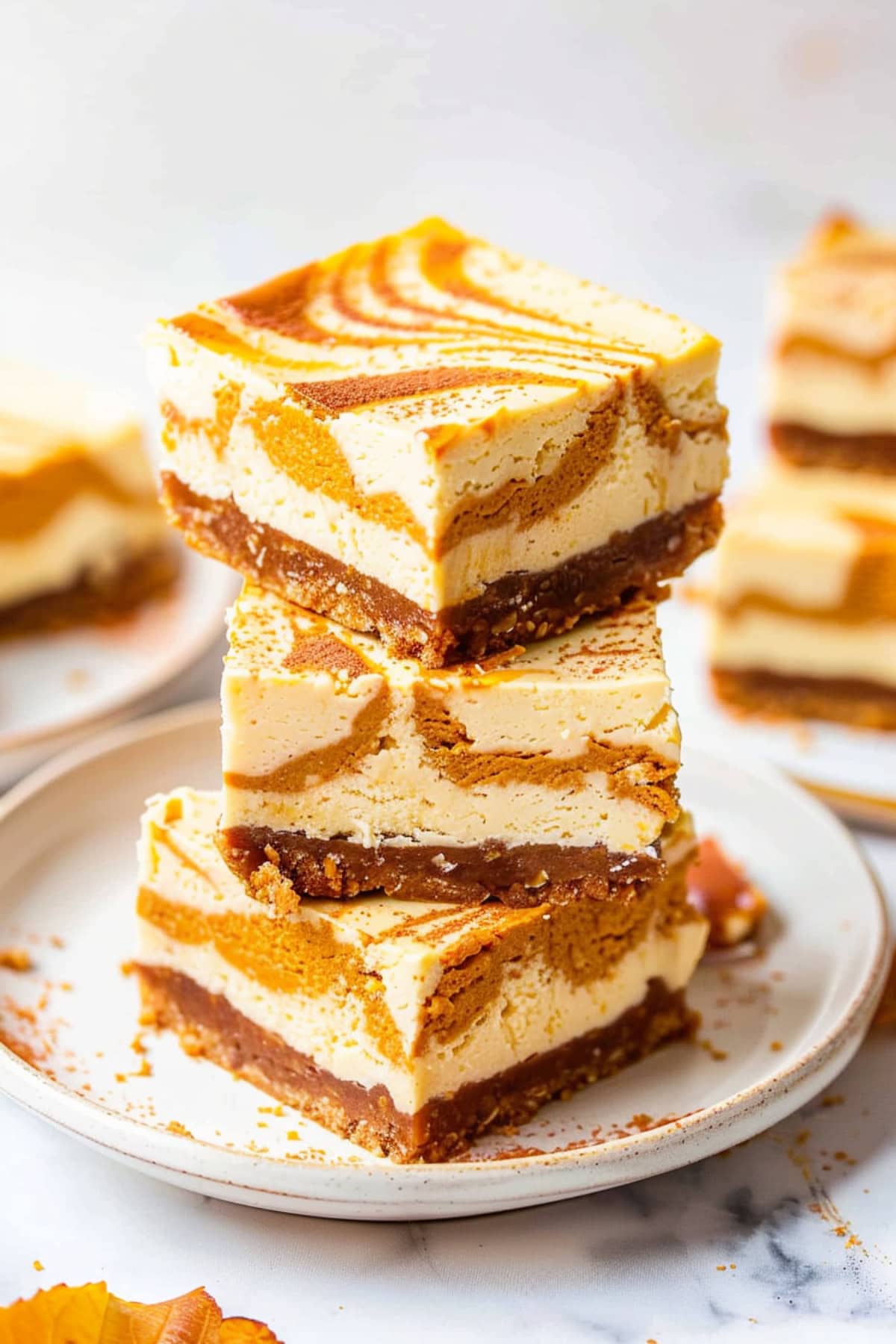 Square slices of Pumpkin Cheesecake Bars stacked in a white plate.