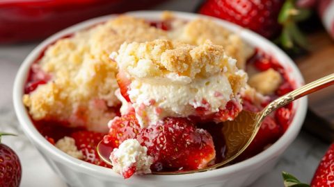 Strawberry Cheesecake Dump Cake scooping out of a bowl, close up