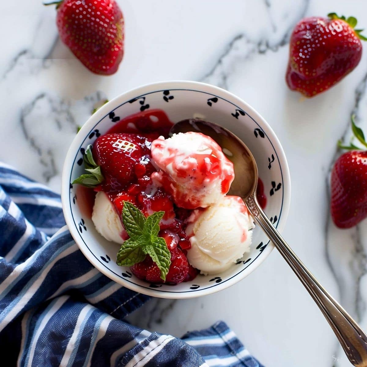Bowl of Vanilla Ice Cream with Strawberry Glaze and Spoon on a White Marble Table with Strawberries All Around