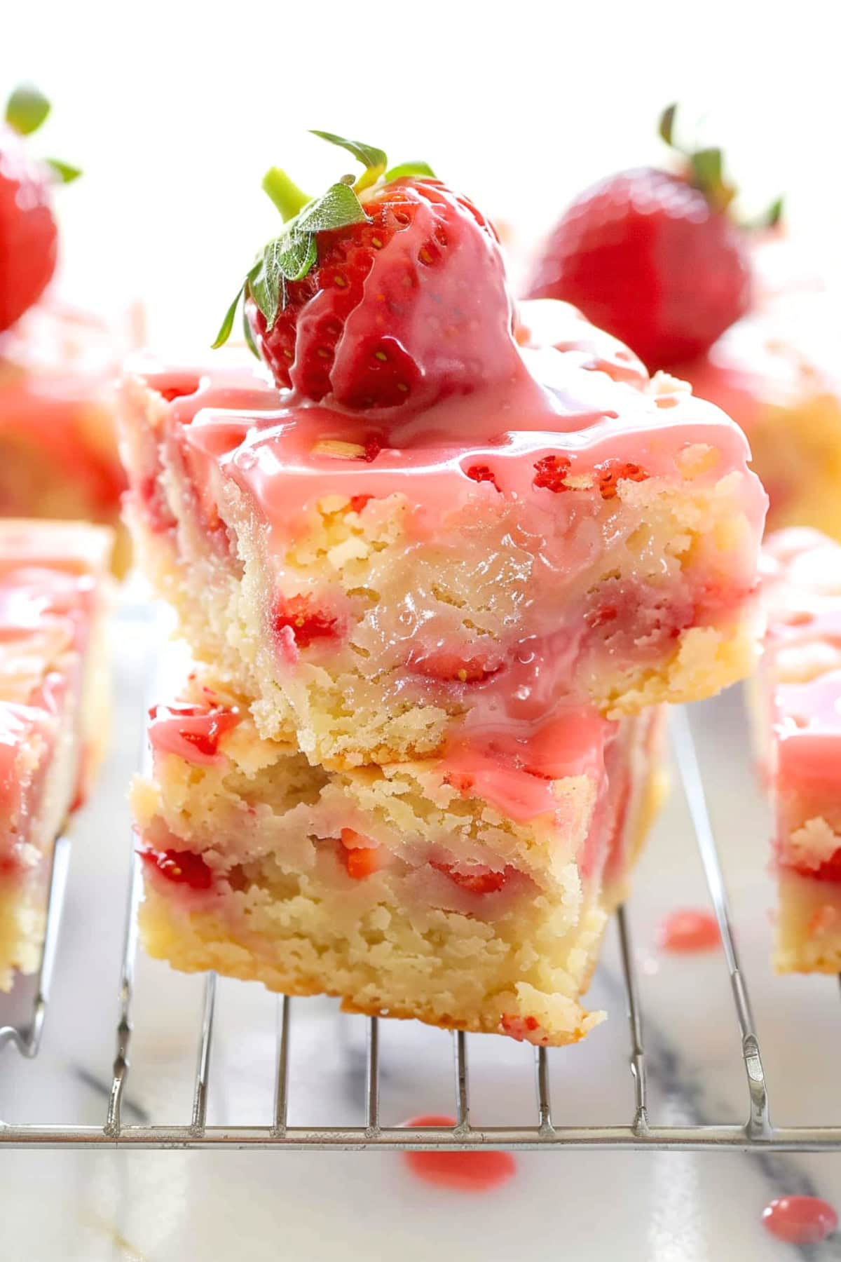 Strawberry lemon blondies in cooling rack drizzled with strawberry glaze.