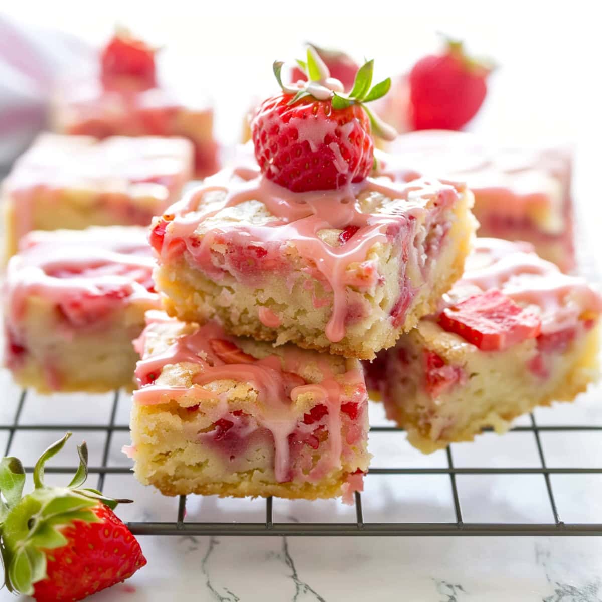 Stack of square slices of strawberry lemon blondies on a cooling rack.