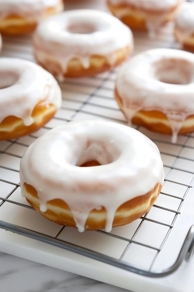 Donuts with sugar glaze on top on a cooling rack.