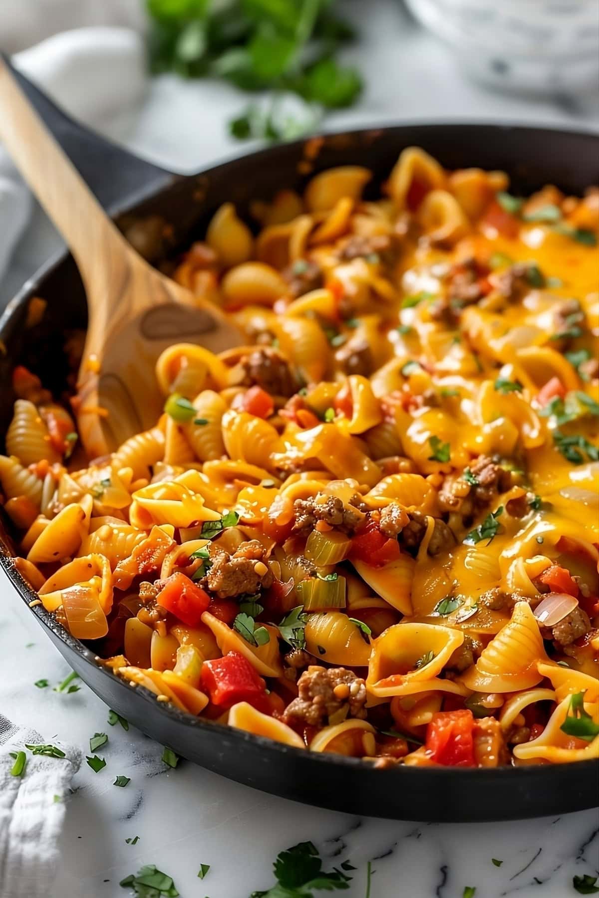 Taco pasta tossed in skillet pan on a with wooden ladle.
