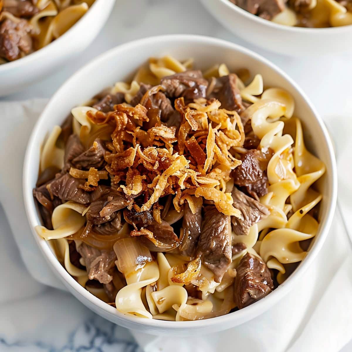 Savory and hearty dish of tender beef, caramelized onions, and egg noodles in a bowl