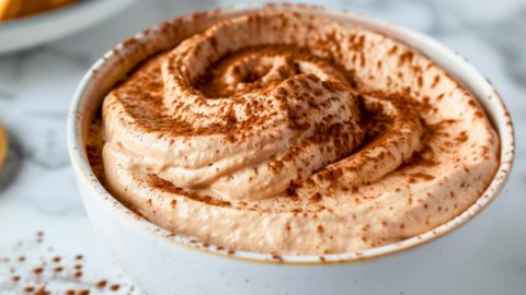 Tiramisu in a white bowl with cocoa powder.