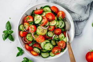 Easy homemade tomato and cucumber salad in a bowl with vinaigrette dressing.