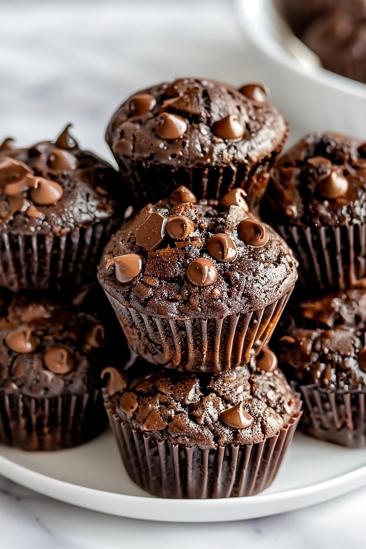 Bunch of triple chocolate muffins  stacked in a white plate.