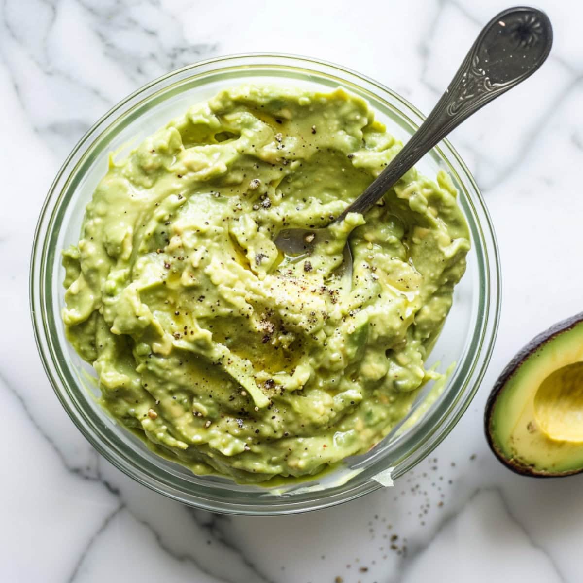 Mashed avocado in a glass bowl.