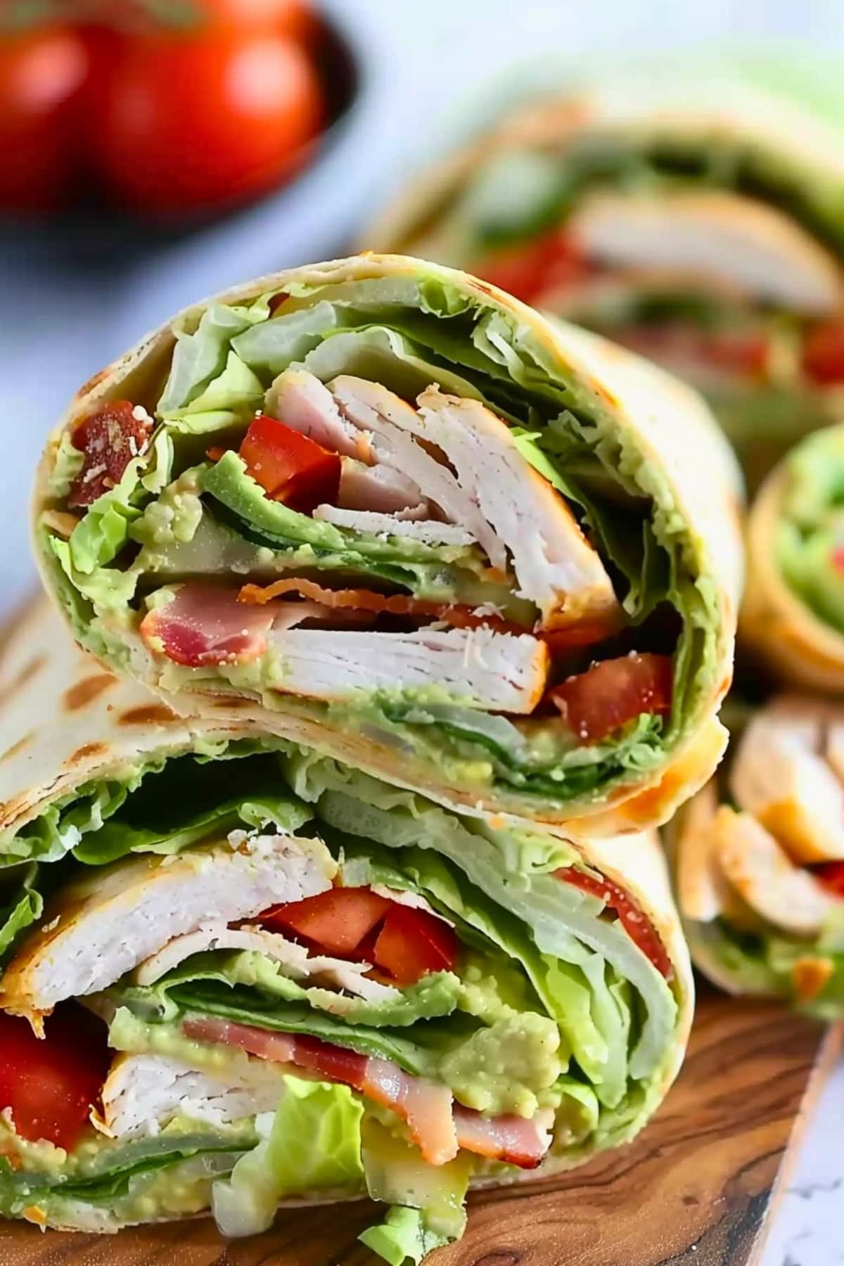Wrap with tomatoes, turkey, smashed avocado, bacon and lettuce filling inside.