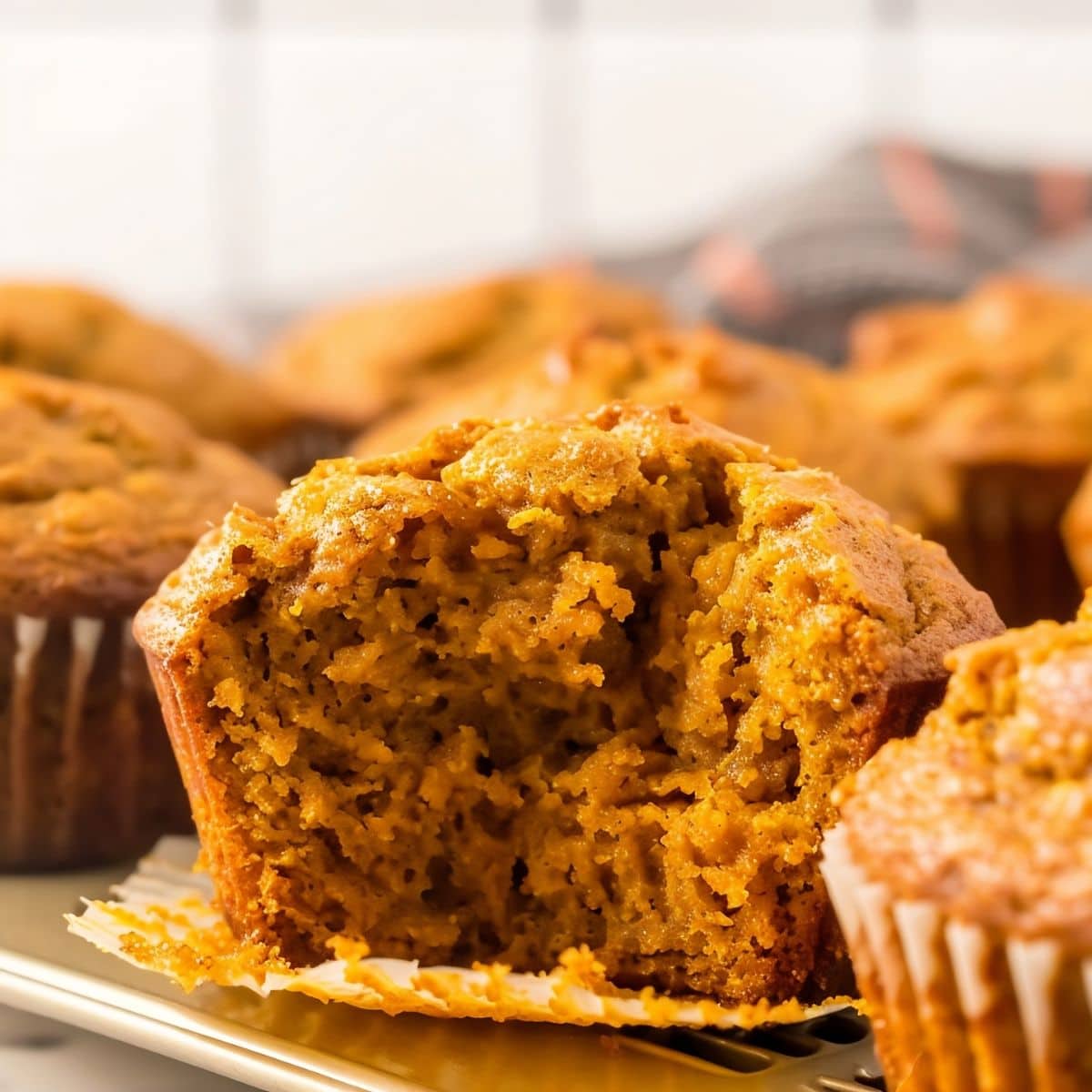 Close up of Two-Ingredient Pumpkin Muffin Missing a Bite with More Muffins Around it
